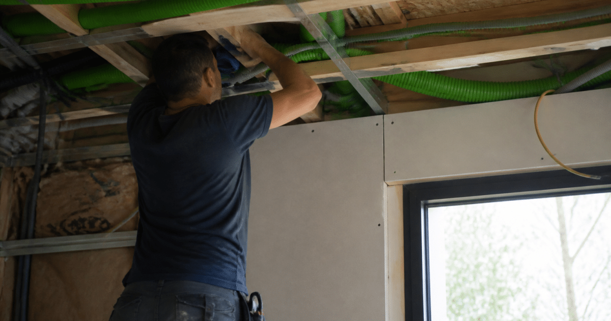 Technicien installant conduits VMC double flux dans plafond