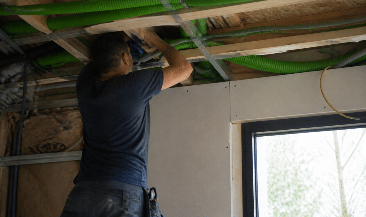 Technicien installant conduits VMC double flux dans plafond