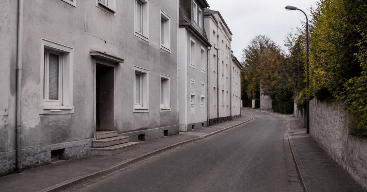 Rue de quartier résidentiel avec immeubles gris et route déserte