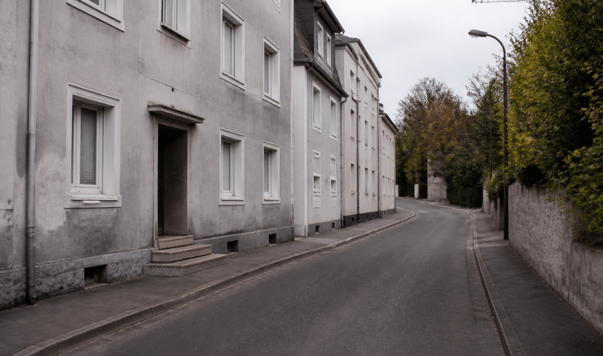 Rue de quartier résidentiel avec immeubles gris et route déserte