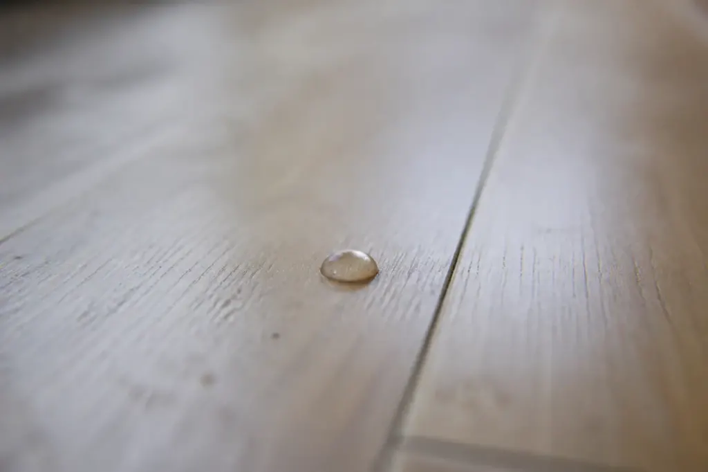 Goutte d'eau perlant sur un parquet clair