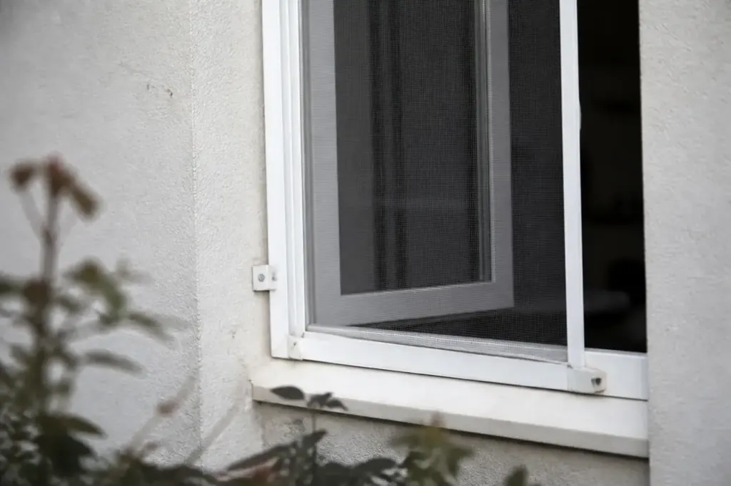 Moustiquaire blanche fixee sur une fenetre ouverte