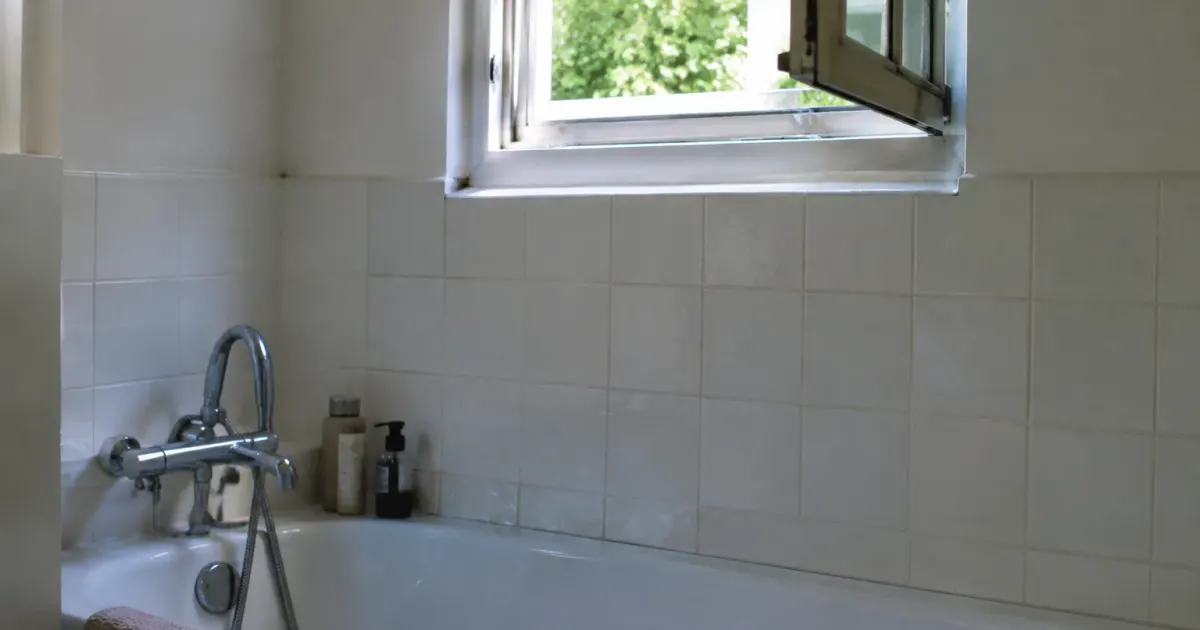 Petite fenetre entrouverte au dessus de la baignoire blanche