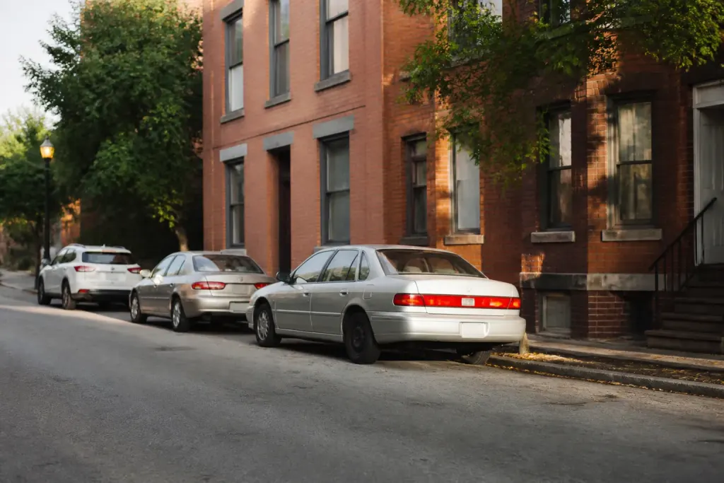 Rue calme avec voitures garees devant immeuble en briques